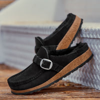 Side view of Birkenstock Buckley with genuine Shearling lining in soft suede black. Matte silver hardware detail and adjustable strap. Latex and cork footbed.