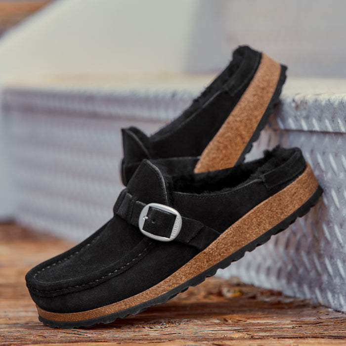 Side view of Birkenstock Buckley with genuine Shearling lining in soft suede black. Matte silver hardware detail and adjustable strap. Latex and cork footbed.