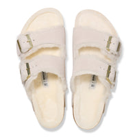 Top detail of the two-strap Birkenstock Arizona Shearling sandal in Antique White suede. Fully lined in genuine shearling over Birkenstock cork latex footbed with gold buckle hardware.