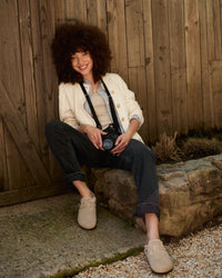 Model wearing Birkenstock Boston Shearling Taupe Clogs with rolled denim and oversized jacket, seated outdoors