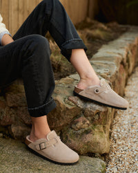 Close-up of Birkenstock Boston Shearling Taupe Clogs on model's feet, styled with black denum in natural light