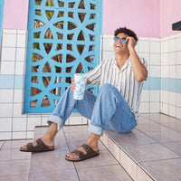 Male lifestyle photo of the Birkenstock Arizona in Mocha Birkibuc, showing two adjustable straps and a cork-latex footbed.
