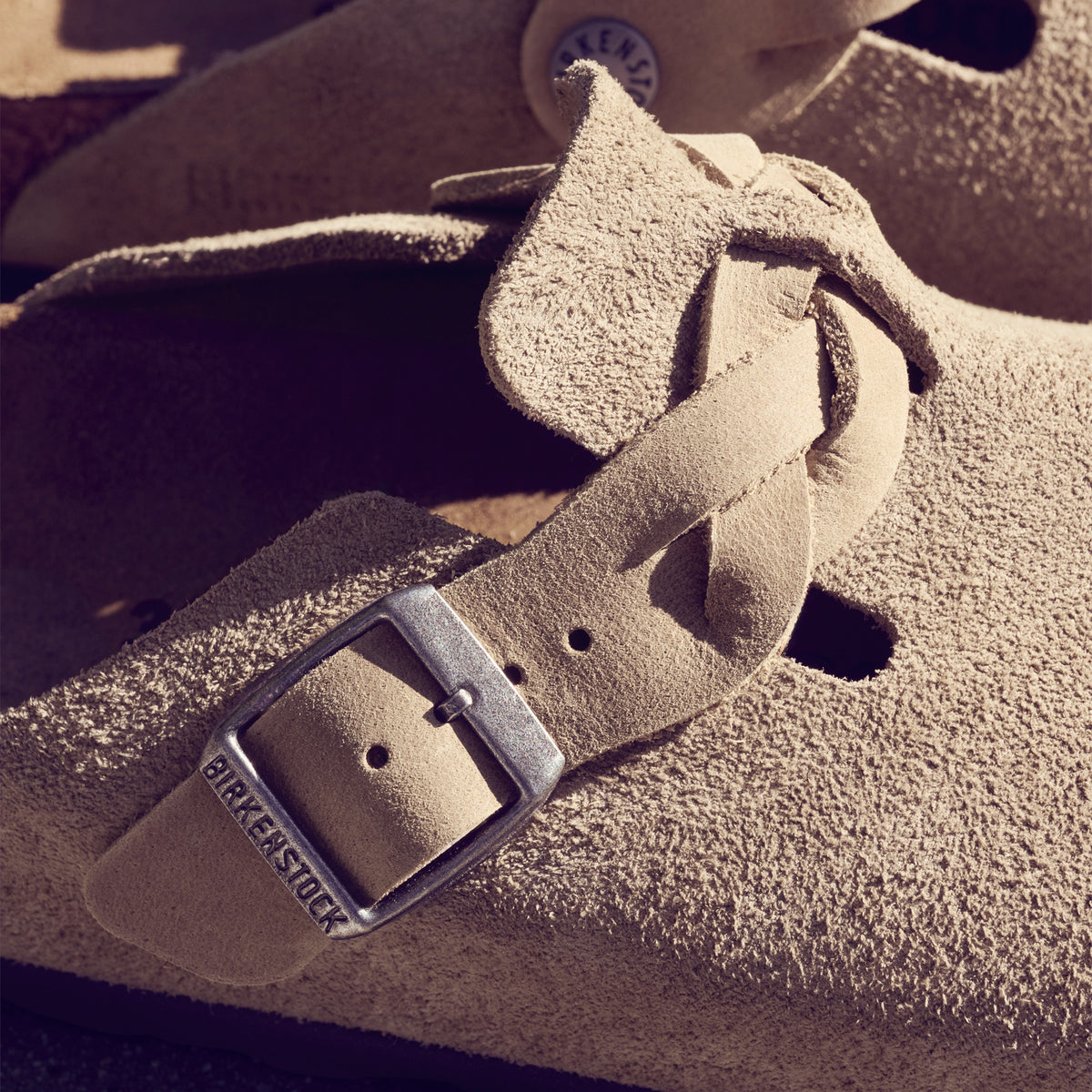 Detail view of the boho-inspired braided Birkenstock Boston Braid in Taupe suede. Classic suede upper with a braided sophisticated strap resting on the Birkenstock original contoured footbed