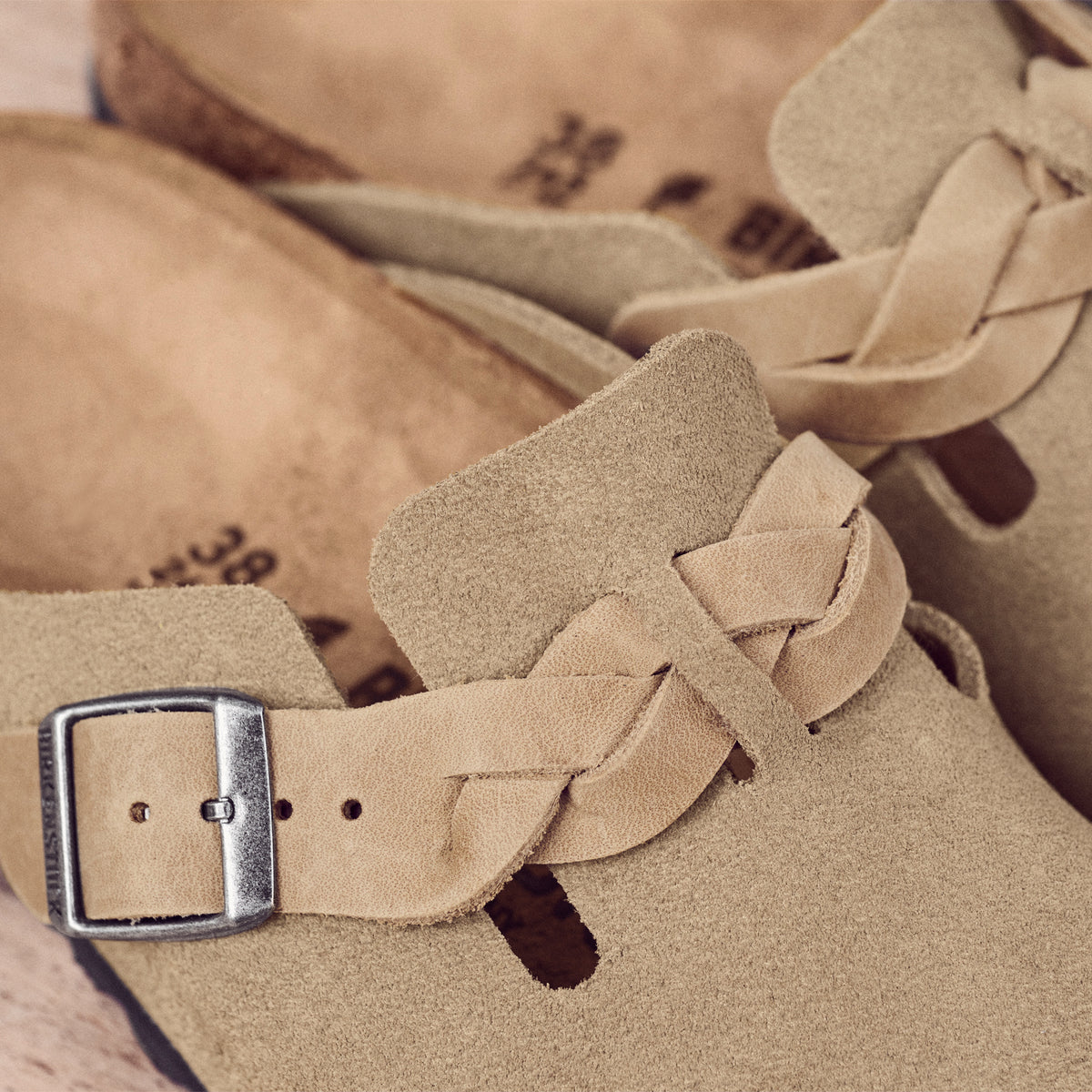 Detail view of the boho-inspired braided Birkenstock Boston Braid in Taupe suede. Classic suede upper with a braided sophisticated strap resting on the Birkenstock original contoured footbed
