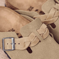Detail view of the boho-inspired braided Birkenstock Boston Braid in Taupe suede. Classic suede upper with a braided sophisticated strap resting on the Birkenstock original contoured footbed