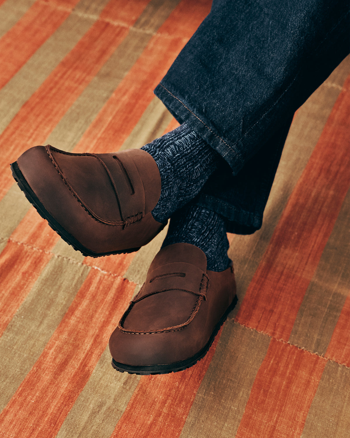 Brown slip on clogs worn with dark jeans on a striped carpet
Birkenstock Naples Clog Wrapped in Habana Oiled Leather