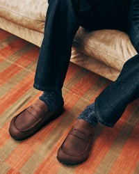Person wearing brown clogs and dark jeans sitting on a beige couch with striped flooring.
Birkenstock Naples Clog Wrapped in Habana Oiled Leather