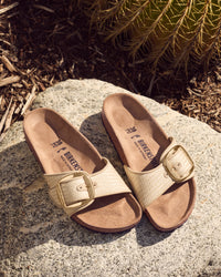 Gold sandals with buckles on a stone surface with a cactus in the background
Birkenstock Madrid Big Buckle Sandal in Raffia Naturale Textile