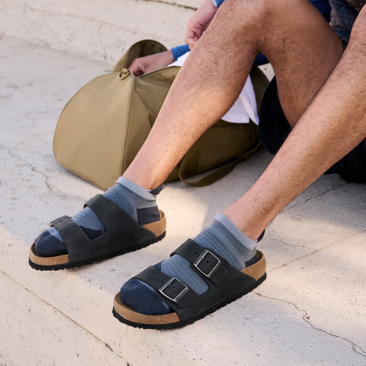 Lifestyle sock and sandal photo of male wearing the Birkenstock Arizona Sandal in Black Oil Leather, unisex sizing.