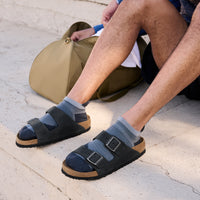 Lifestyle sock and sandal photo of male wearing the Birkenstock Arizona Sandal in Black Oil Leather, unisex sizing.