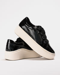 Rear side angle of both sneakers showing patent shine and off-white platform base