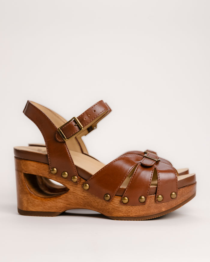 The Dansko Alanna in Tan leather is a standout piece from Dansko’s Ashland collection, designed for those who want a high-fashion silhouette without the usual discomfort of a tall heel. Every pair is handmade in Brazil, featuring a genuine wood wedge that has been hand-carved, sanded, and flame-burnished for a one-of-a-kind finish. The sculpted 3.5-inch heel is balanced by a 1.5-inch platform, creating a manageable 2-inch effective slope that provides height while maintaining stability.
