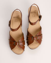 The Dansko Alanna in Tan leather is a standout piece from Dansko’s Ashland collection, designed for those who want a high-fashion silhouette without the usual discomfort of a tall heel. Every pair is handmade in Brazil, featuring a genuine wood wedge that has been hand-carved, sanded, and flame-burnished for a one-of-a-kind finish. The sculpted 3.5-inch heel is balanced by a 1.5-inch platform, creating a manageable 2-inch effective slope that provides height while maintaining stability.