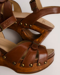 The Dansko Alanna in Tan leather is a standout piece from Dansko’s Ashland collection, designed for those who want a high-fashion silhouette without the usual discomfort of a tall heel. Every pair is handmade in Brazil, featuring a genuine wood wedge that has been hand-carved, sanded, and flame-burnished for a one-of-a-kind finish. The sculpted 3.5-inch heel is balanced by a 1.5-inch platform, creating a manageable 2-inch effective slope that provides height while maintaining stability.