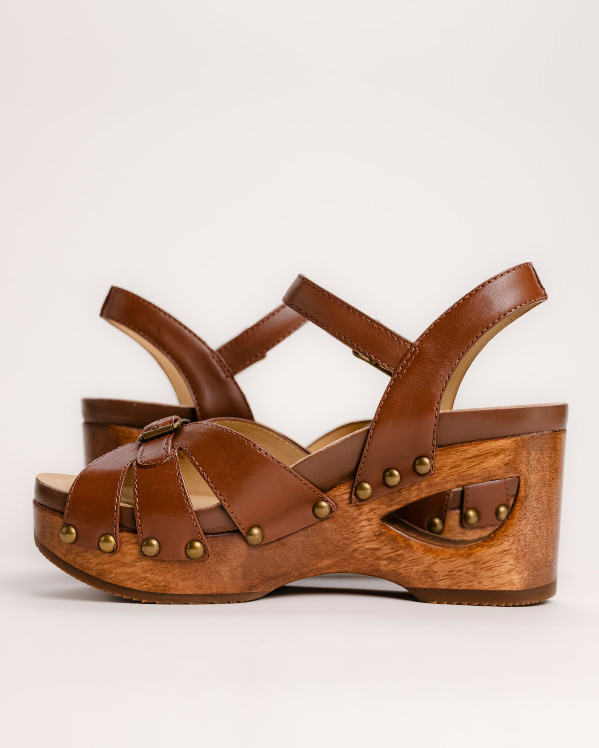 The Dansko Alanna in Tan leather is a standout piece from Dansko’s Ashland collection, designed for those who want a high-fashion silhouette without the usual discomfort of a tall heel. Every pair is handmade in Brazil, featuring a genuine wood wedge that has been hand-carved, sanded, and flame-burnished for a one-of-a-kind finish. The sculpted 3.5-inch heel is balanced by a 1.5-inch platform, creating a manageable 2-inch effective slope that provides height while maintaining stability.