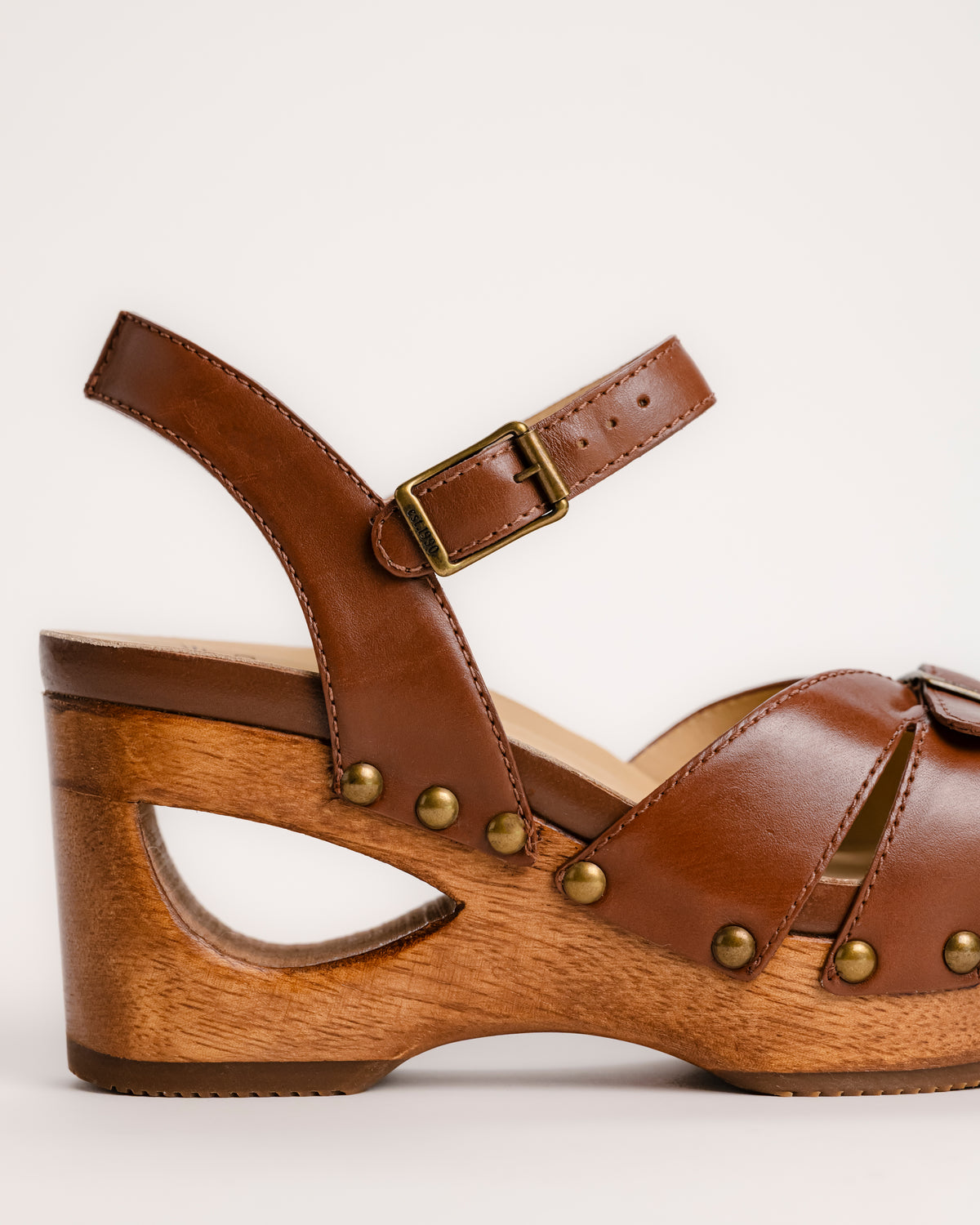 The Dansko Alanna in Tan leather is a standout piece from Dansko’s Ashland collection, designed for those who want a high-fashion silhouette without the usual discomfort of a tall heel. Every pair is handmade in Brazil, featuring a genuine wood wedge that has been hand-carved, sanded, and flame-burnished for a one-of-a-kind finish. The sculpted 3.5-inch heel is balanced by a 1.5-inch platform, creating a manageable 2-inch effective slope that provides height while maintaining stability.