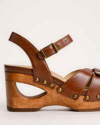 The Dansko Alanna in Tan leather is a standout piece from Dansko’s Ashland collection, designed for those who want a high-fashion silhouette without the usual discomfort of a tall heel. Every pair is handmade in Brazil, featuring a genuine wood wedge that has been hand-carved, sanded, and flame-burnished for a one-of-a-kind finish. The sculpted 3.5-inch heel is balanced by a 1.5-inch platform, creating a manageable 2-inch effective slope that provides height while maintaining stability.