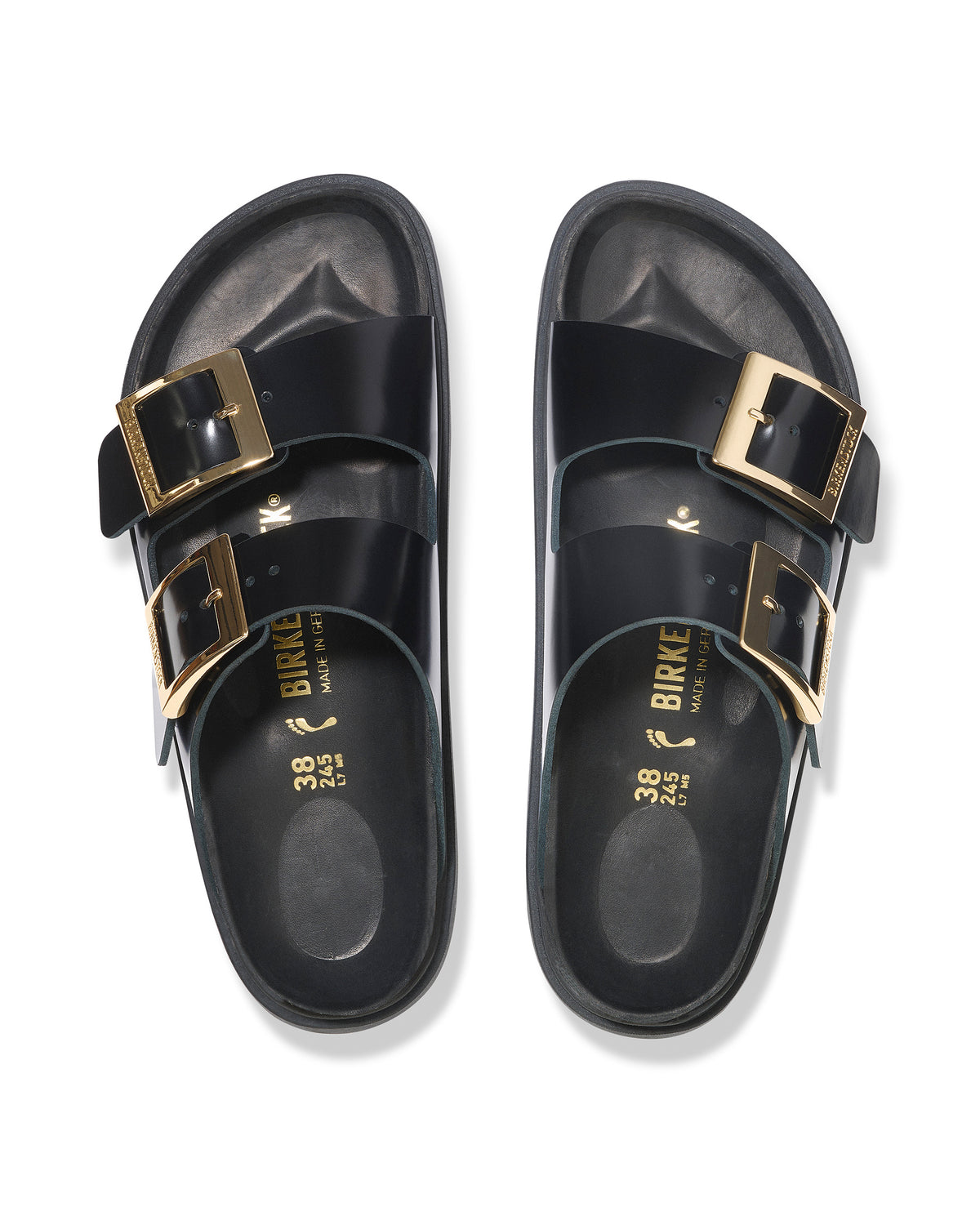 Black Birkenstock two-strap high-shine leather sandals with gold buckles on a white background