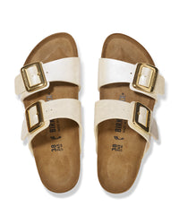 Pair of pearl white Birkenstock Sydney Luxe Buckle sandals with gold buckles on a white background