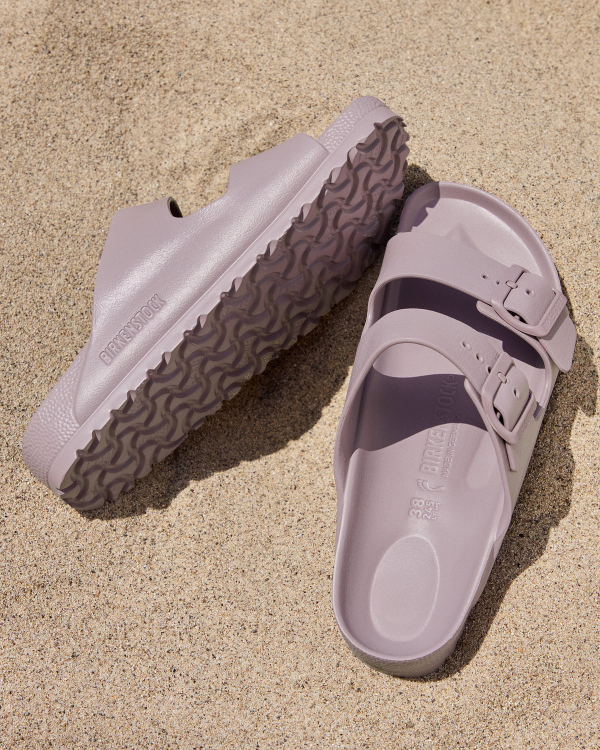 Pair of Birkenstock EVA Arizona Faded Purple two-strap water-ready sandals on a sandy surface