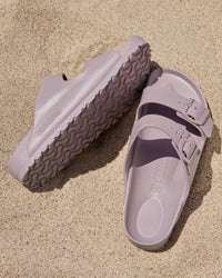 Pair of Birkenstock EVA Arizona Faded Purple two-strap water-ready sandals on a sandy surface