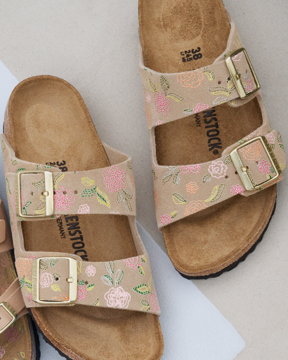 Pair of Birkenstock Arizona floral-pattern printed taupe suede sandals on a light background. 1031736
