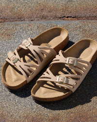The Birkenstock Granada offers a refined, natural aesthetic for those who appreciate the support of a classic slide but want a more detailed look. This version is upgraded with premium nubuck leather, which is gently buffed to create a soft, velvety texture that feels luxurious from the first wear. The twin-strap design features elegant laser-cut perforations, providing a light and airy feel that transitions perfectly from a casual day out to a more put-together summer evening.