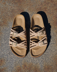 The Birkenstock Granada offers a refined, natural aesthetic for those who appreciate the support of a classic slide but want a more detailed look. This version is upgraded with premium nubuck leather, which is gently buffed to create a soft, velvety texture that feels luxurious from the first wear. The twin-strap design features elegant laser-cut perforations, providing a light and airy feel that transitions perfectly from a casual day out to a more put-together summer evening.