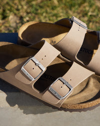 The Birkenstock Arizona is essentially the gold standard for slides, and this Birkibuc version is the practical answer for anyone who wants a rugged, low-maintenance look. Instead of traditional leather, these are crafted from a signature Birkenstock material called Birkibuc—a heavy-duty synthetic with a brushed finish that mimics the texture of real nubuck. It’s tough, easy to wipe down, and holds its shape through seasons of wear.