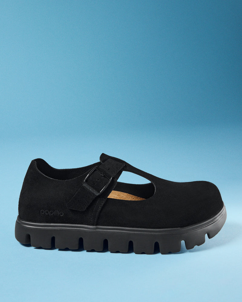 A Birkenstock Paris Chunky Mary Jane Platform in Black Suede Leather with a thick, textured lug sole, shown from a side profile against a solid blue background. The brand name 'papillio' is subtly printed in white on the heel area.