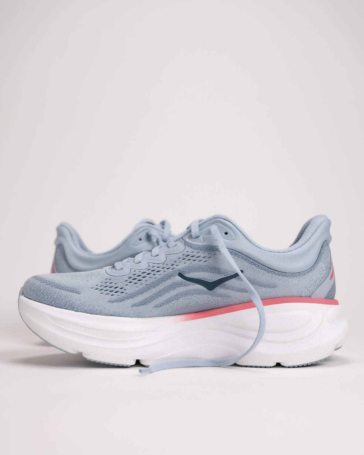Light blue HOKA running shoes with a salmon/pink accent on a light background