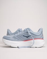 Light blue HOKA running shoes with a salmon/pink accent on a light background