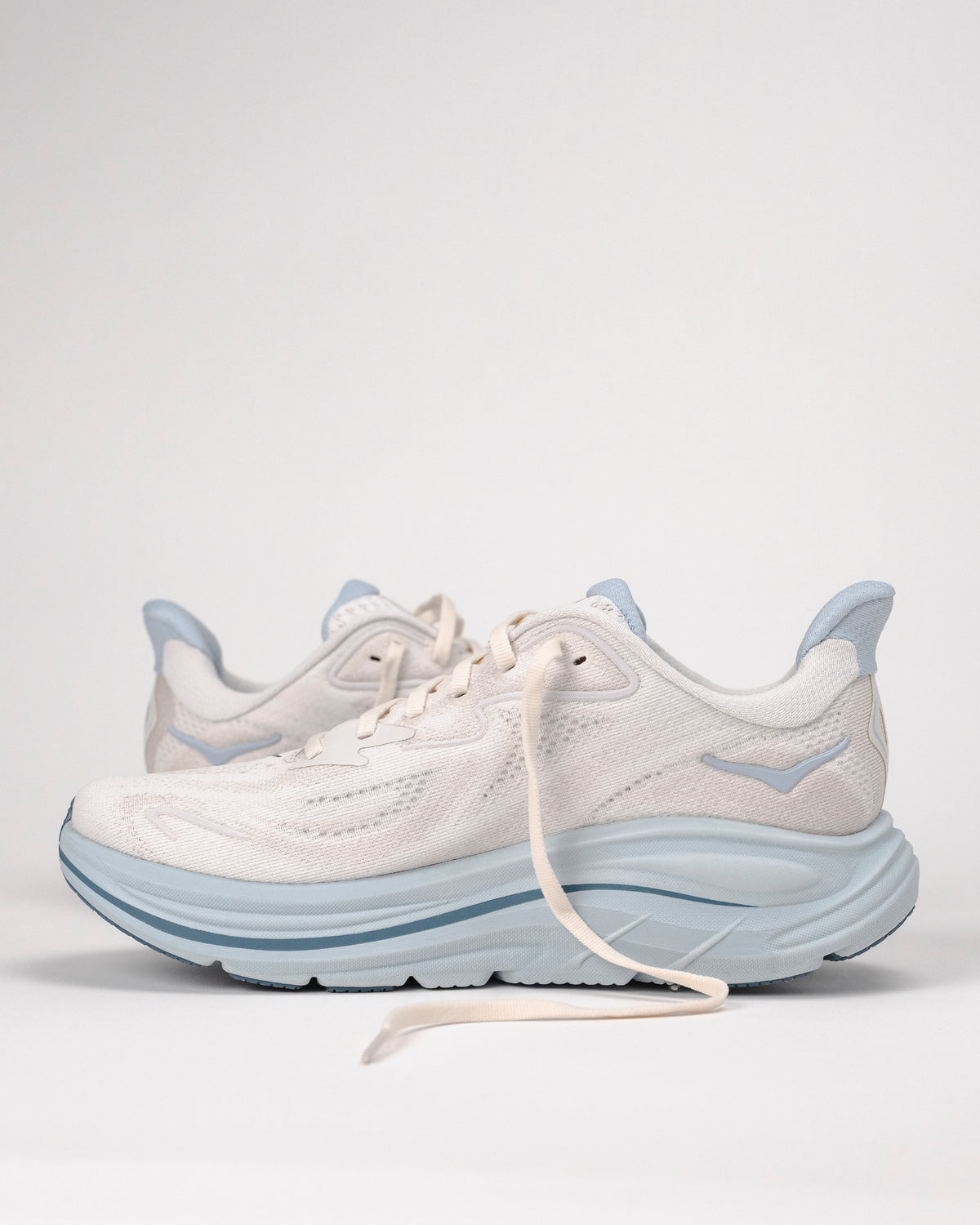 Off white and light blue HOKA Clifton 10 running shoes on a white background