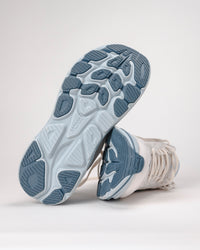 Bottom view of off white and light blue HOKA Clifton 10 running shoes for women on a white background.