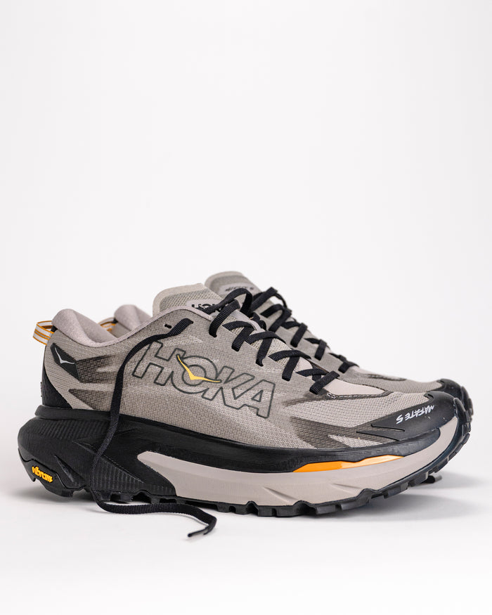 Gray and black HOKA Mafate 5 max-cushion trail running athletic shoe with 'HOKA' brand logo on a white background