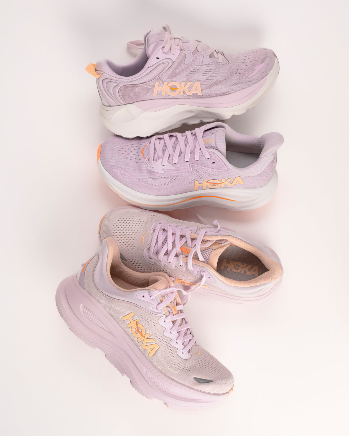 Women's HOKA Gaviota 6, Clifton 10, and Bondi 9 in Lilac purple colorway with orange peachy highlights. Cushioned running shoes for women.