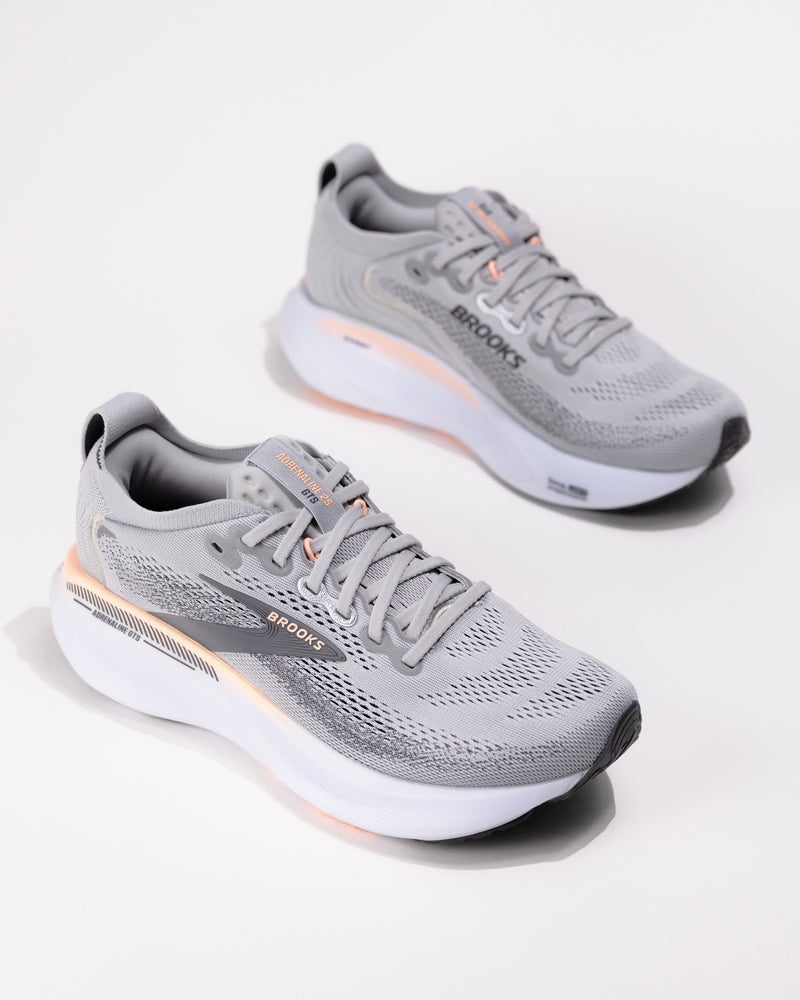Dynamic angle of the Brooks Adrenaline GTS 25 in Grey/Coral with coral accents and logo