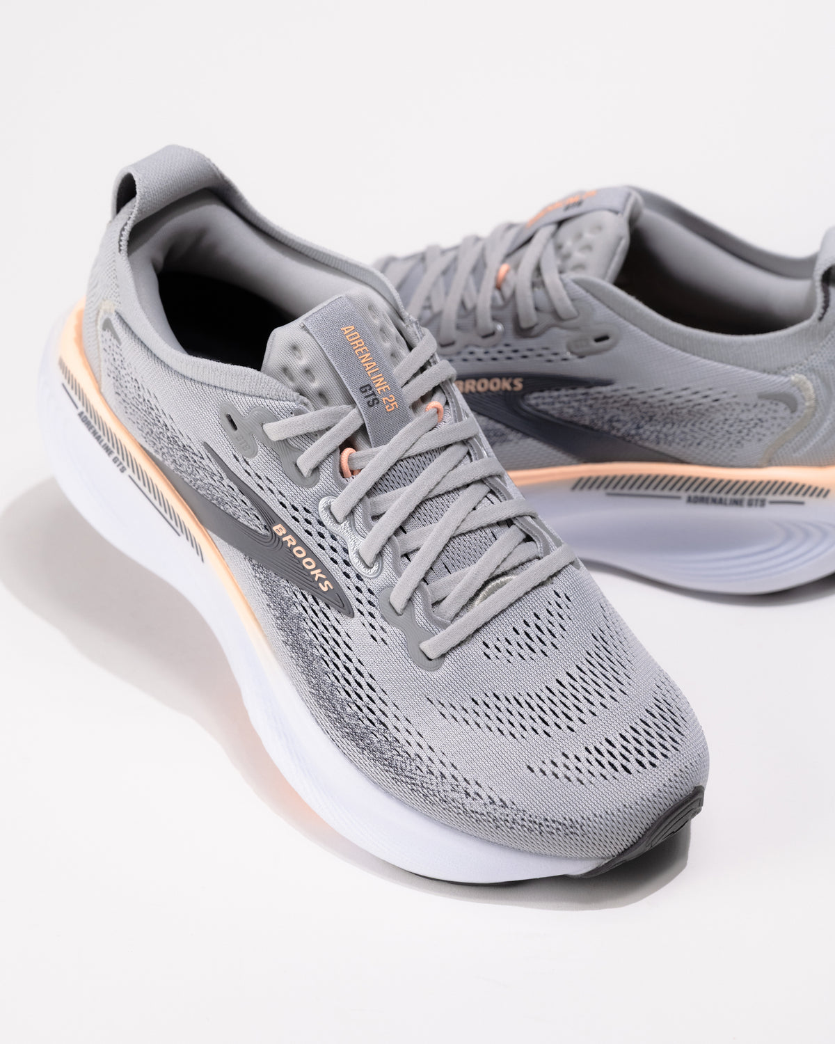 Dynamic angle of the Brooks Adrenaline GTS 25 in Grey/Coral with coral accents and logo