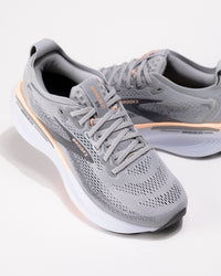 Dynamic angle of the Brooks Adrenaline GTS 25 in Grey/Coral with coral accents and logo