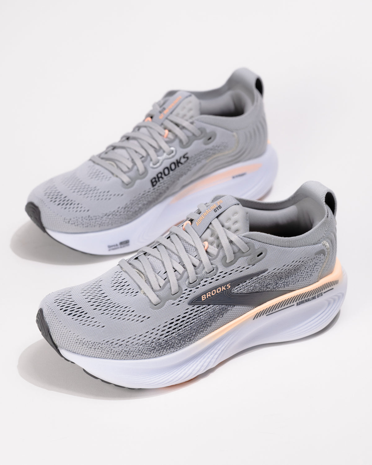 Dynamic angle of the Brooks Adrenaline GTS 25 in Grey/Coral with coral accents and logo