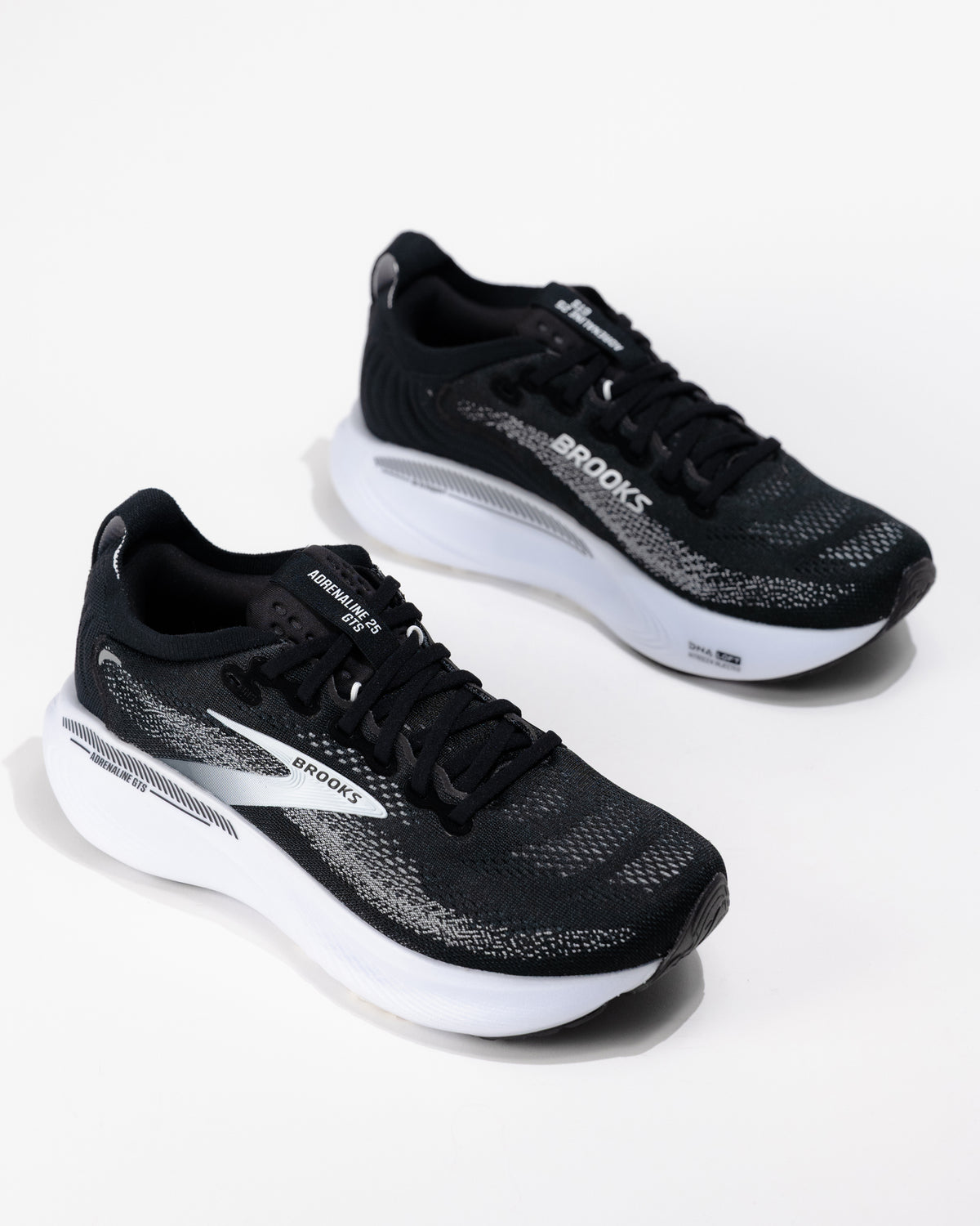 Dynamic angle of the Brooks Adrenaline GTS 25 in black/grey/white, a women's cushioned running shoe