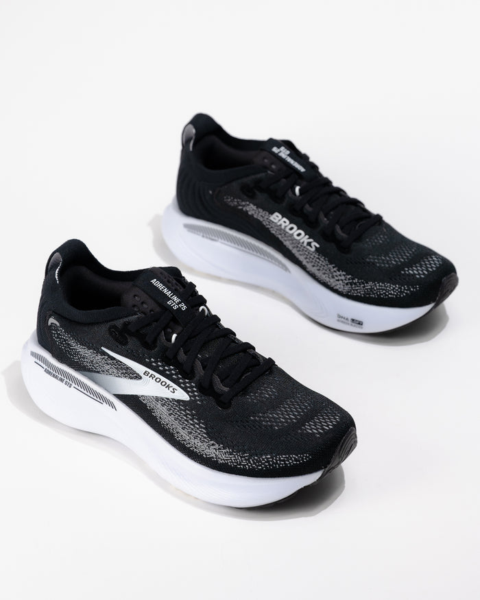 Dynamic angle of the Brooks Adrenaline GTS 25 in black/grey/white, a women's cushioned running shoe