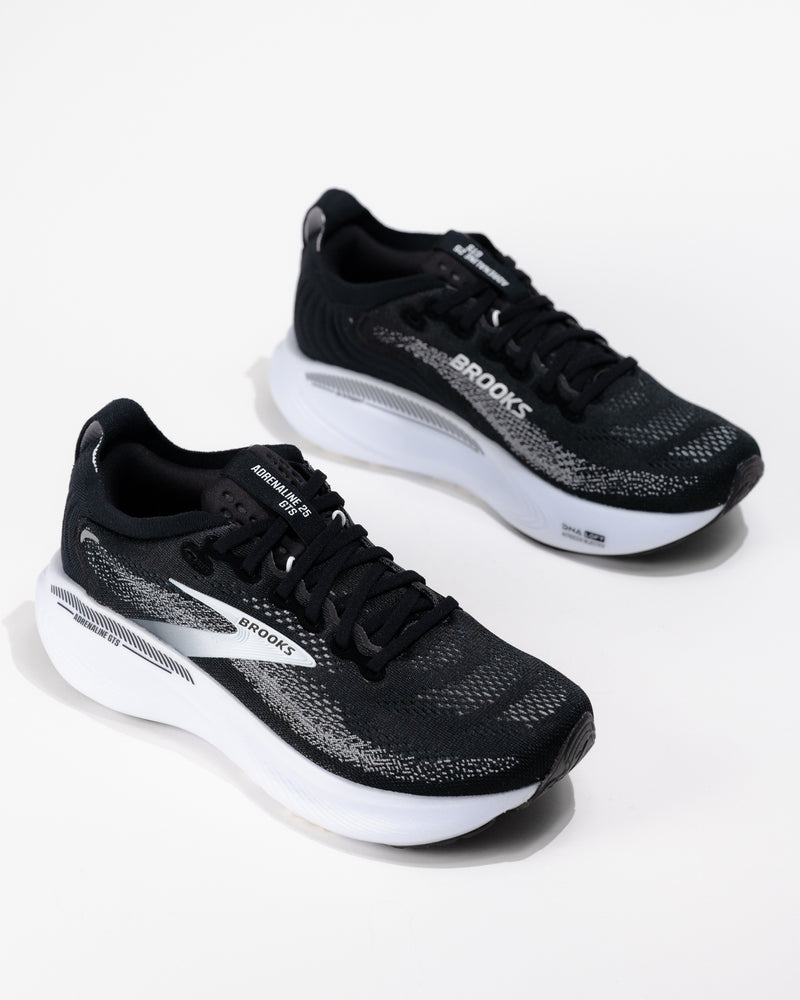 Dynamic angle of the Brooks Adrenaline GTS 25 in black/grey/white, a women's cushioned running shoe