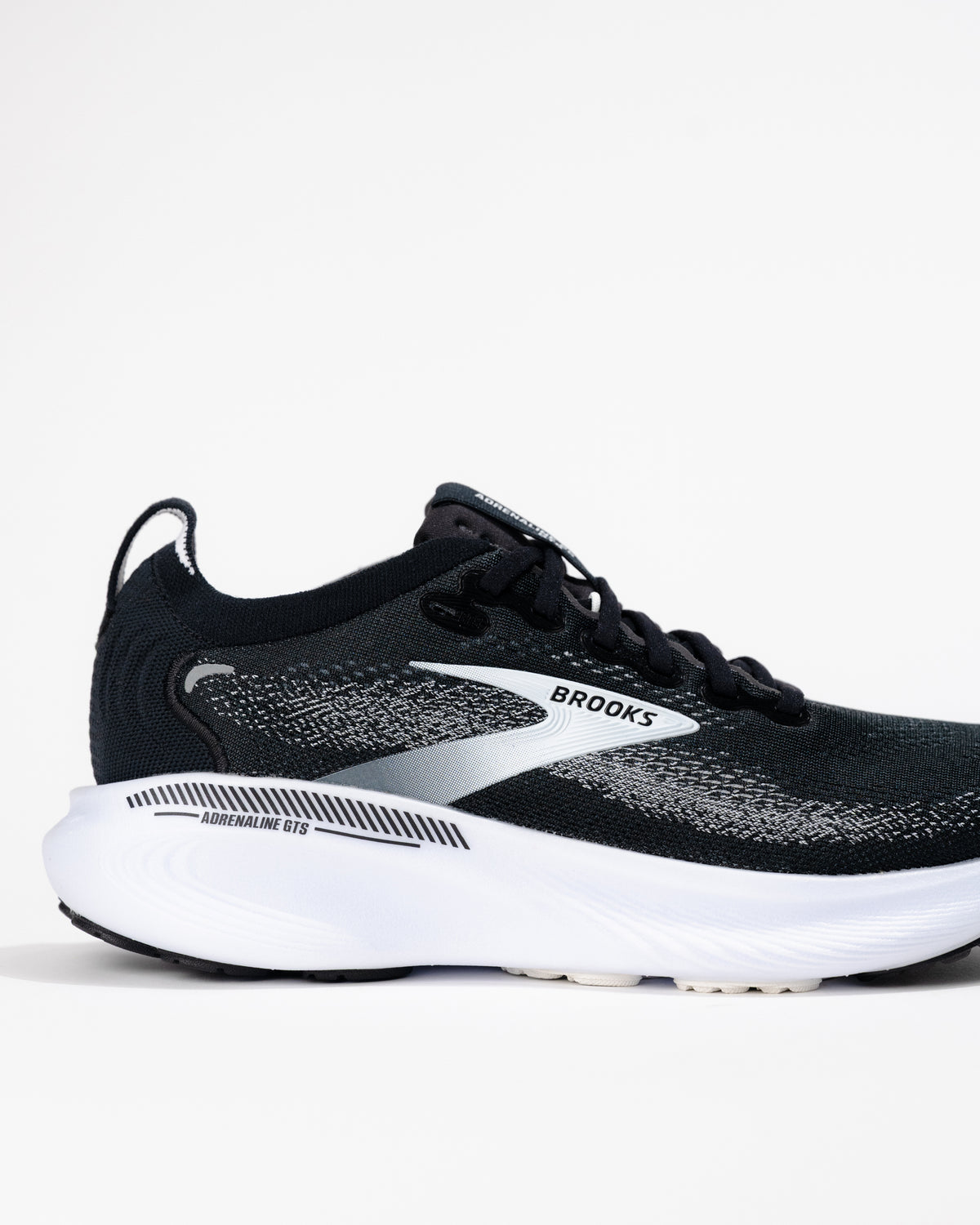 Detail back side view of the Women's Brooks Adrenaline GTS 25 running shoe in Black/White showing logo and upper mesh texture.