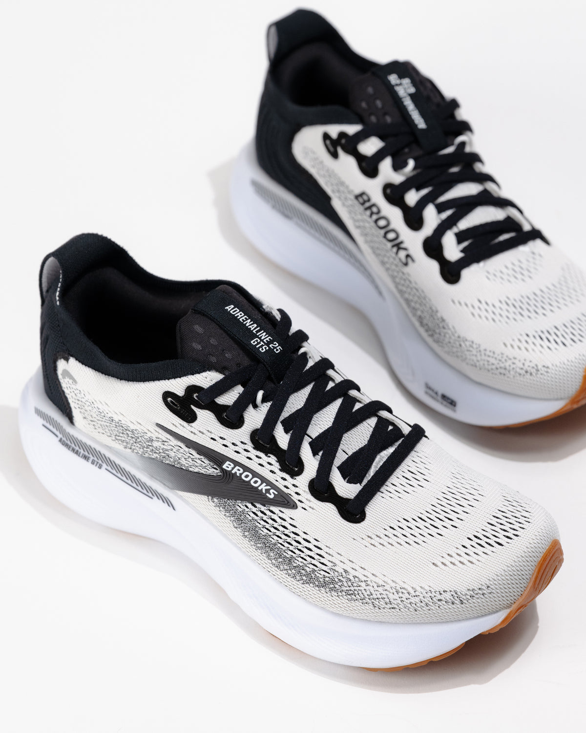 Three-quarter angle of Women's Brooks Adrenaline GTS 25 in White/Black/Gum, highlighting dual-density foam midsole and streamlined silhouette.