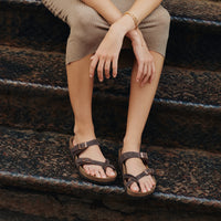 Lifestyle photo of a female wearing the Birkenstock footbed and adjustable leather straps on the Women's Birkenstock Mayari Slip-On Sandal in Habana Oiled Leather