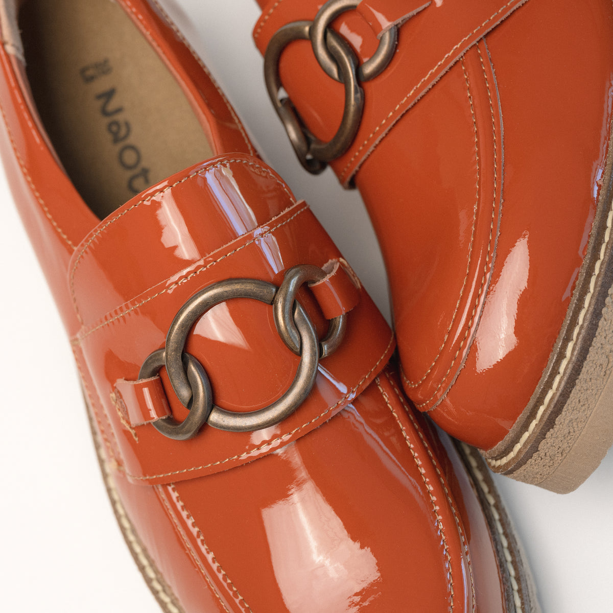 Chain link ornament detail on the Burnt Orange patent leather loafer by Naot for women. A modern take on a classic loafer design.