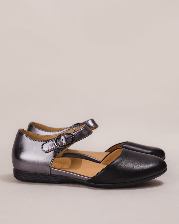 Side profile of the Dansko Liv Mary Jane Flat in black/pewter leather showing buckle and low-profile outsole.