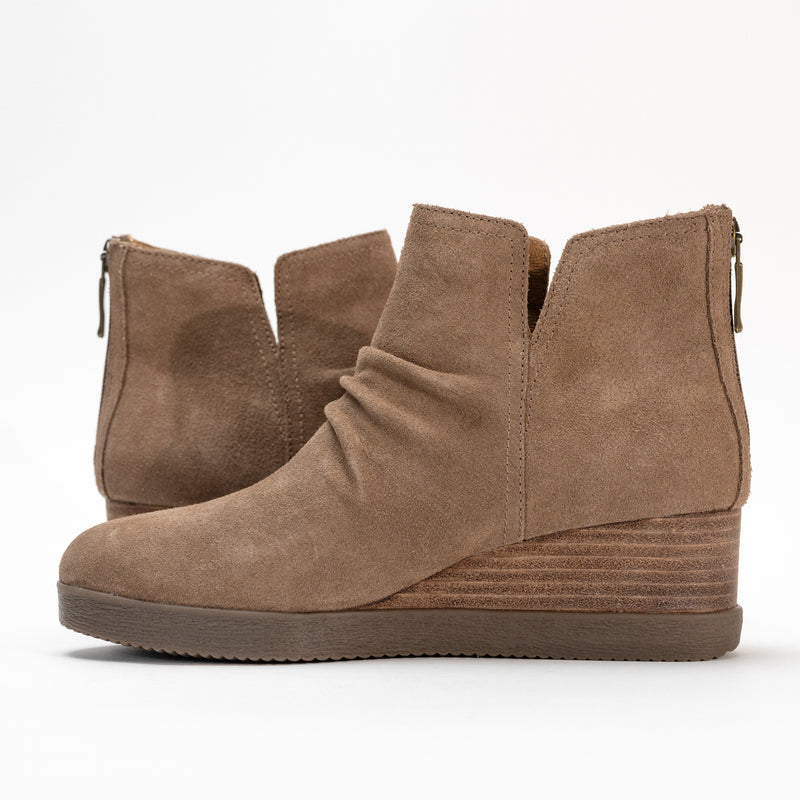 Close-up of the raw leather stacked wedge heel and cut-out waterproof suede upper.