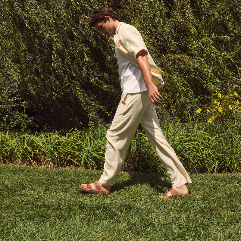 Lifestyle image of a male wearing the Birkenstock Arizona sandal in Cognac Oiled Leather in a spring outfit.